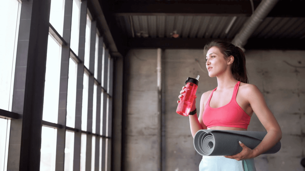 Das Mädchen setzt eine Flasche Wasser und Teppich
